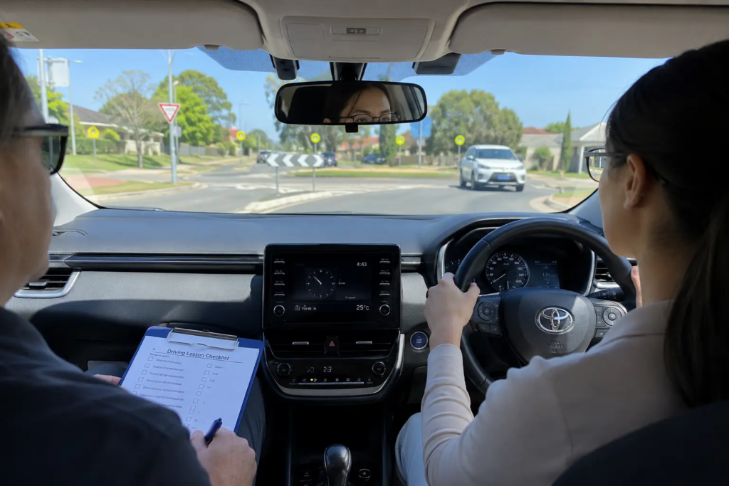 Driving instructor reviewing lesson checklist while student practices driving at a roundabout in Sydney